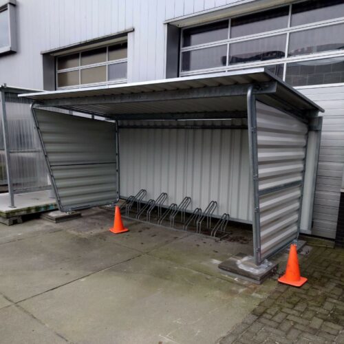 Fietsoverkapping Karin 53 Fietsoverkapping model Karin lengte 4.3m met achterwand en zijwanden van trapeziumplaat. Deze fietsoverkapping is gemonteerd op prefab betonpoeren 30x30cm.